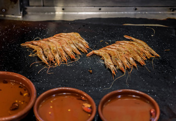 Traditional gambas a la plancha or grilled shrimp tapas being cooked on a hot plate in Madrid, Spain