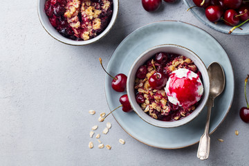 Cherry crumble with ice cream in bowl. Grey background. Copy space. Top view.