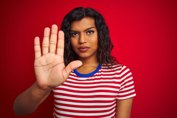 Beautiful transsexual transgender woman wearing stiped t-shirt over isolated red background with open hand doing stop sign with serious and confident expression, defense gesture