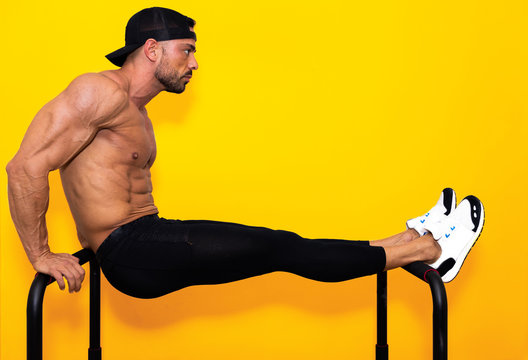 very muscular fitness model man, without shirt, training in parallel bars