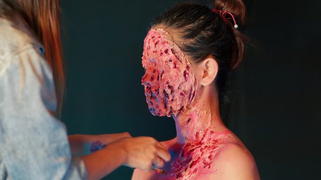 Make up artist painting body and face of girl with blood, scars and wounds.