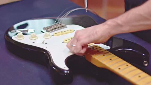 Luthier removes pickguard from guitar