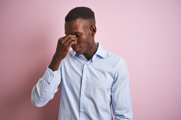 African american man wearing blue elegant shirt standing over isolated pink background tired rubbing nose and eyes feeling fatigue and headache. Stress and frustration concept.