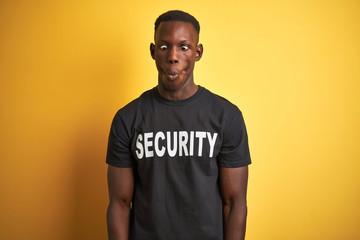 African american safeguard man wearing security uniform over isolated yellow background making fish...