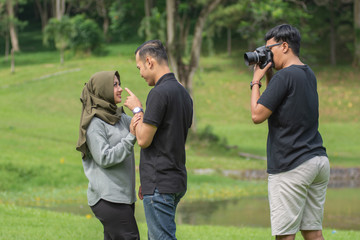 Asian young Muslim couples are enjoying being together by dancing in the open green area with...