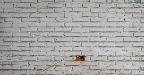 Old white colored brick blocks wall with dusty and uncompleted hole drilled for electrical cable...