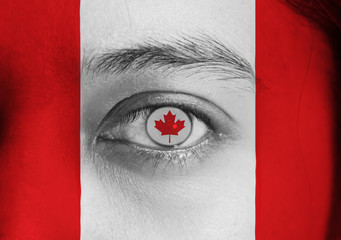 Human face painted Canada flag with the red maple leaf on the center of eye or eyeball. Human eye painted with flag of Canada.