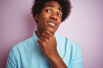 Young american man with afro hair wearing blue shirt standing over isolated pink background serious face thinking about question, very confused idea