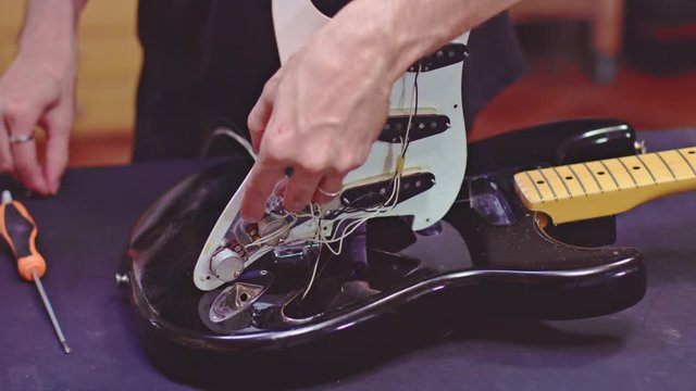 Luthier fixing electrical components of a guitar