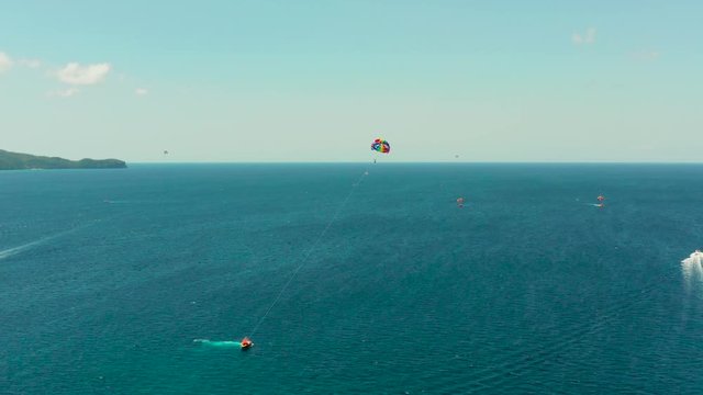 Tourists on a parachute over the sea, aerial view. Tourists parasailing on the Boracay, Philippines.