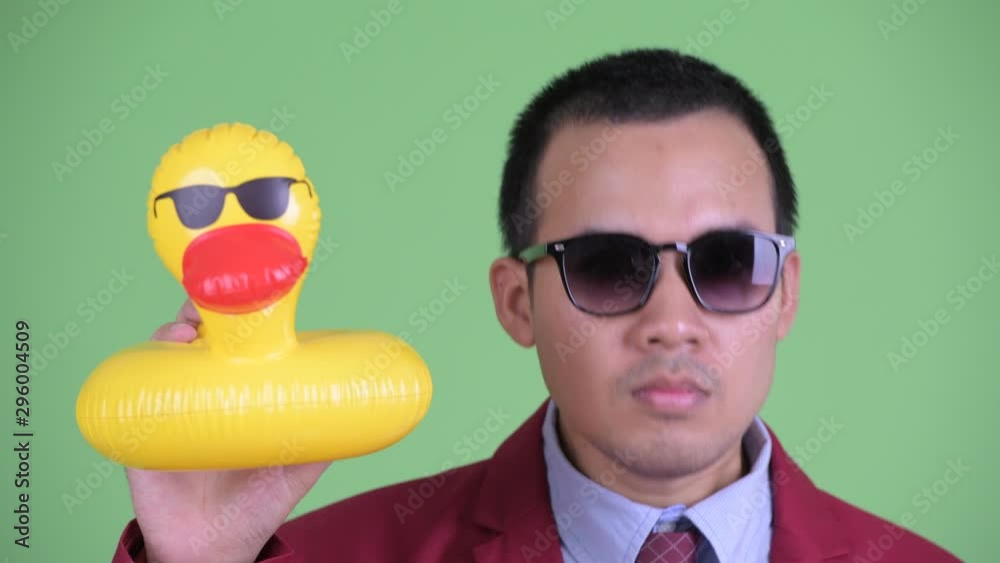 Canvas Prints Asian businessman in suit with sunglasses holding inflatable duck ready to party