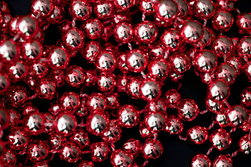 Shiny red garland on a dark surface close up. Abstract christmas background