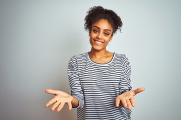 African american woman wearing navy striped t-shirt standing over isolated white background smiling cheerful offering hands giving assistance and acceptance.