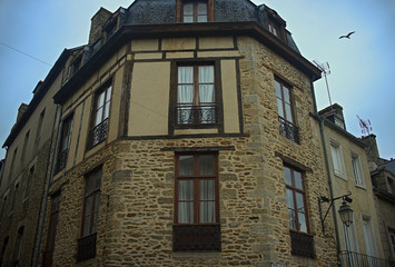Fototapeta na wymiar Old traditional French stone corner building with wooden windows