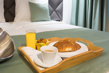 Breakfast in bed, hotel bedroom interior