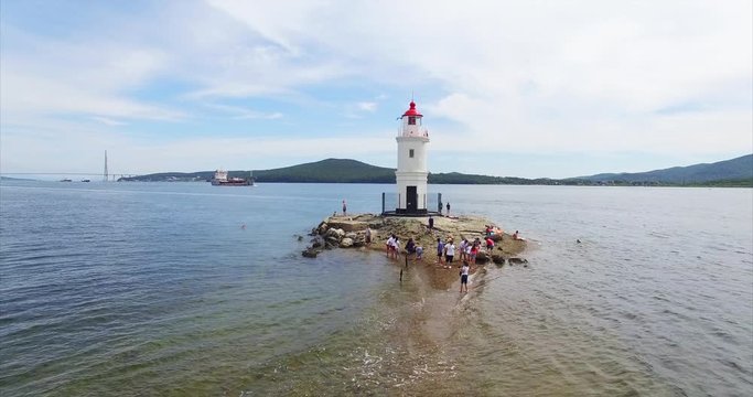 Aerial zooming out view of Tokarevsky lighthouse in Vladivostok and tourists came here to take pictures of nice landscape. Summer day. Russia