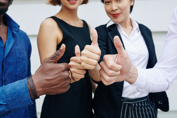 Close-up image of business people showing thumbs-up to express support