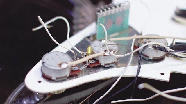 Guitar maker soldering electrical parts of a guitar