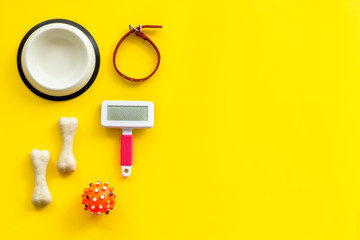 Pet's accessories like bones, collar and bowl on yellow background top view flat lay frame space for text