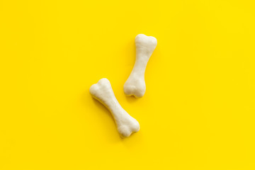 Food and toys for dogs. Chewing bones on yellow background top view copy space