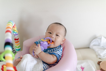 Baby with toy in mouth on play gym