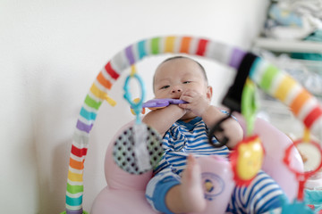 Baby with toy in mouth on play gym