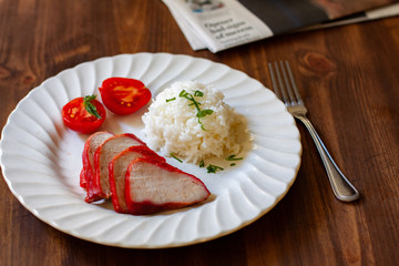 roast pork with rice and tomato on white plate