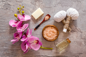 Massage table with thai herbal balls and orchids on grey background top view pattern