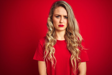 Young beautiful woman wearing basic t-shirt standing over red isolated background skeptic and nervous, frowning upset because of problem. Negative person.
