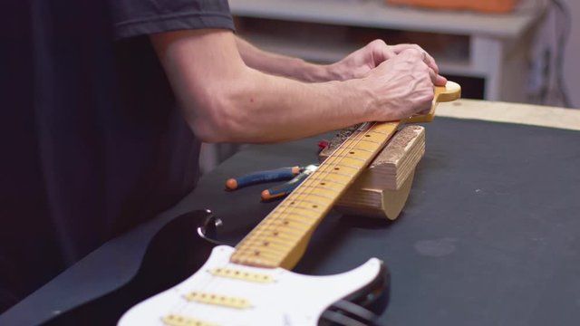 Luthier wrap strings of a guitar