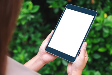 Mockup image of a woman holding black tablet pc with blank white desktop screen in the park