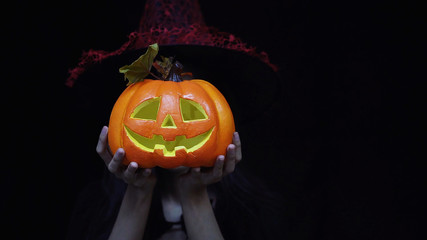 Woman in Halloween costume holding Halloween pumpkin or Jack O Lantern instead of head