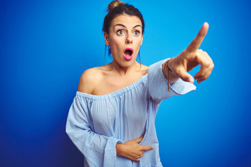 Young beautiful woman wearing bun hairstyle over blue isolated background Pointing with finger...