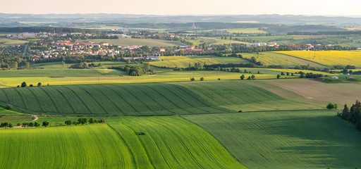 Breathtaking aerial shot of green fields on hills next to small settlement
