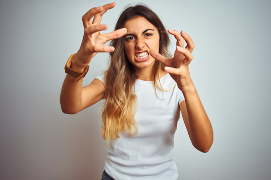 Young beautiful woman wearing casual white t-shirt over isolated background Shouting frustrated with rage, hands trying to strangle, yelling mad