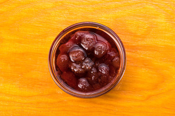 bread on a brown plate next to strawberry jam and with a mug of milk on a wooden background