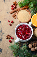 Cranberry sauce with ingredients on a wooden background.