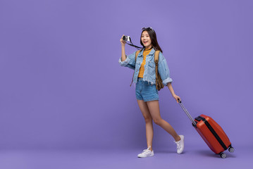 Smiling Asian tourist girl with camera and baggage