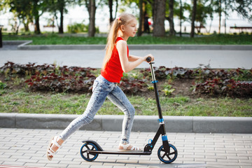 Teen Child riding a scooter in a city park. © olgasparrow