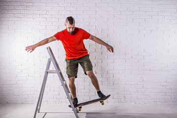 Skateboarder performing a trick on a skateboard on the background of a white wall.