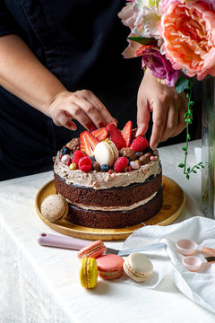 Hand chef put stawberry Raspberry and Blueberry  on choccolate cake