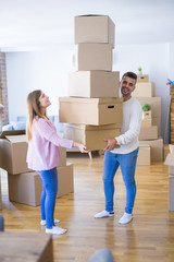 Fototapeta na wymiar Young couple moving to a new house holding cardboard boxes worried about falling for overweight
