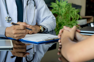 Closeup male medical doctor or physician in white lab coat with stethoscope writing information of...