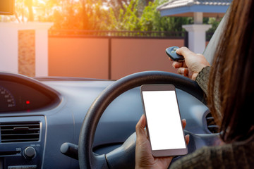 man in car, hand using remote control to open the automatic gate while using mobile smartphone with...