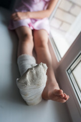 Fototapeta na wymiar Broken leg in a medical plaster on a windowsill