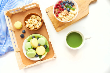 matcha green tea, breakfast top view white background. oatmeal with berries, toasts on a wooden tray, nuts, coffee