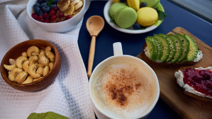 breakfast top view black background. oatmeal with berries, toasts on a wooden tray, nuts, coffee