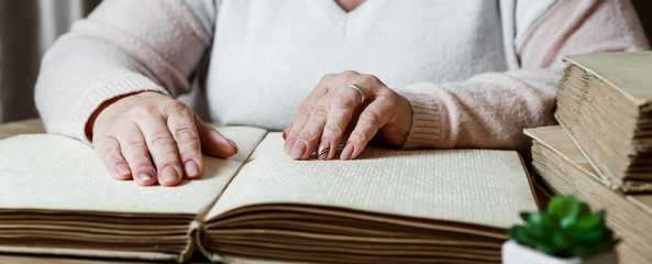 woman reading braille text on old book