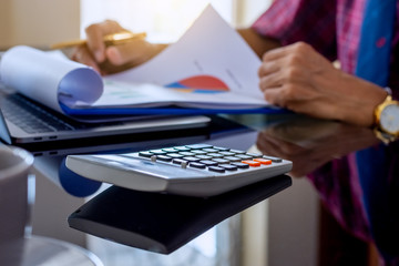Business man working on document data paper with calculator at office.