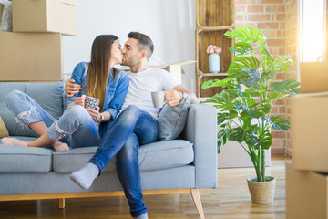 Obraz premium Young couple moving to a new home relaxing sitting on the sofa while drinking a cup of coffee, smiling happy for moving to new apartment